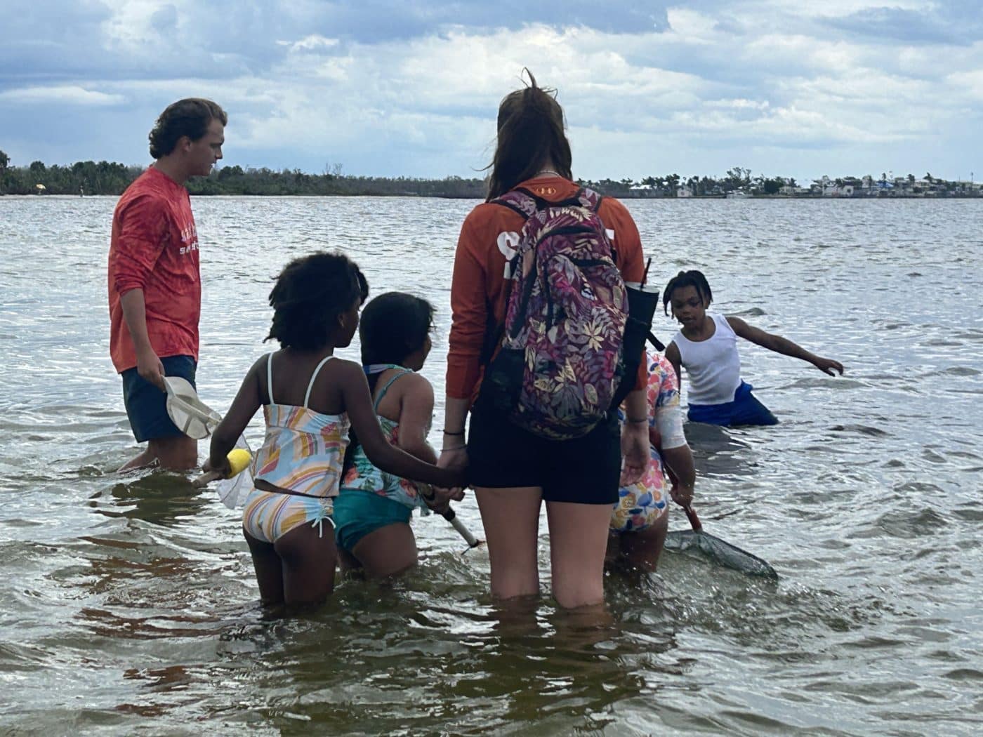 Marine science educators Austin Wise and Annie Clinton lead Sanibel Sea School students into the waters at Bunche Beach with dip nets in hand, ready to find ocean treasures.